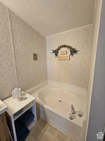 Built-in corner soaking tub with chrome fixtures and light-colored patterned wall paneling