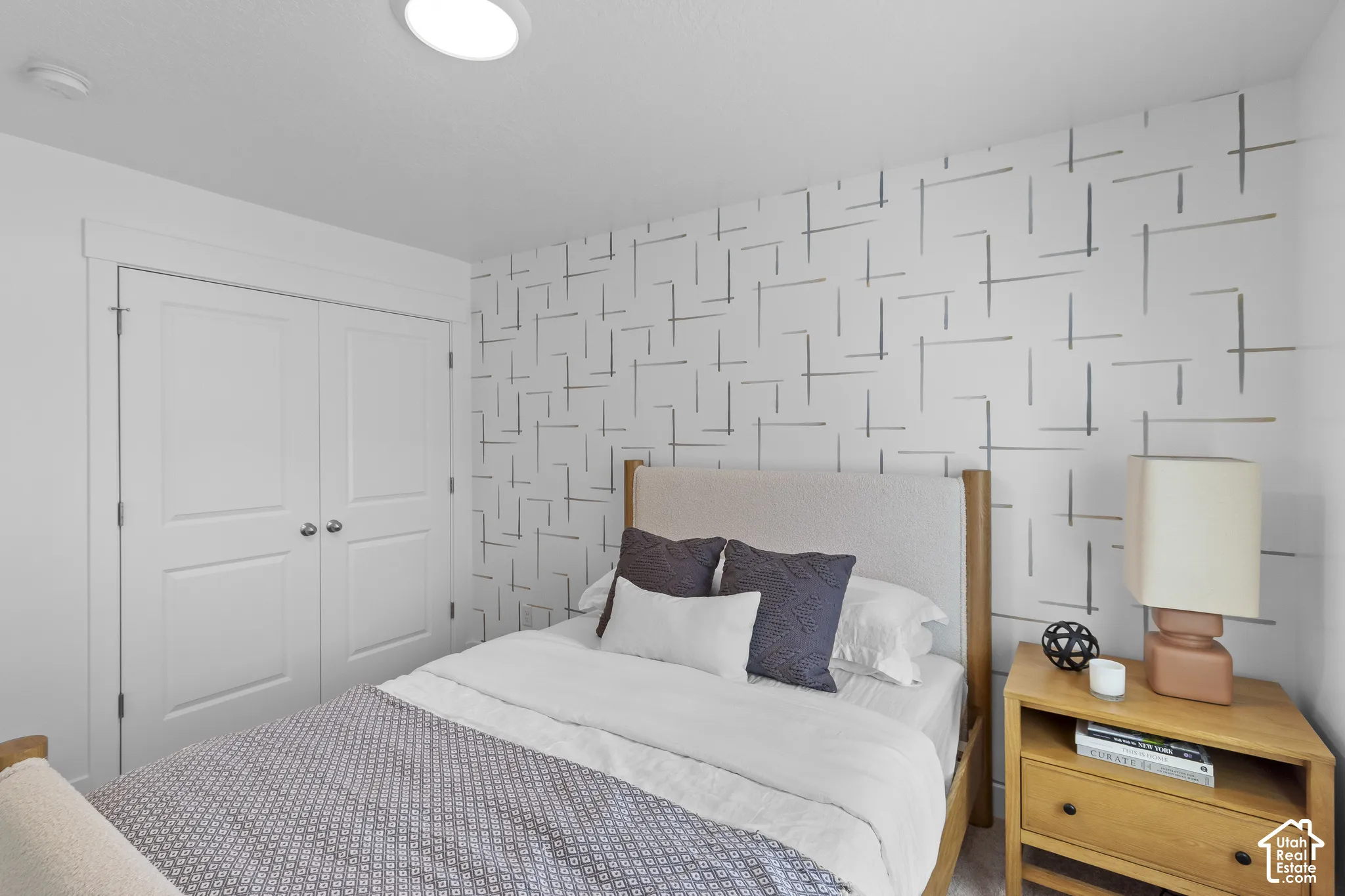 Recessed lighting, patterned accent wall, two-panel closet doors, and wood-finish bed frame