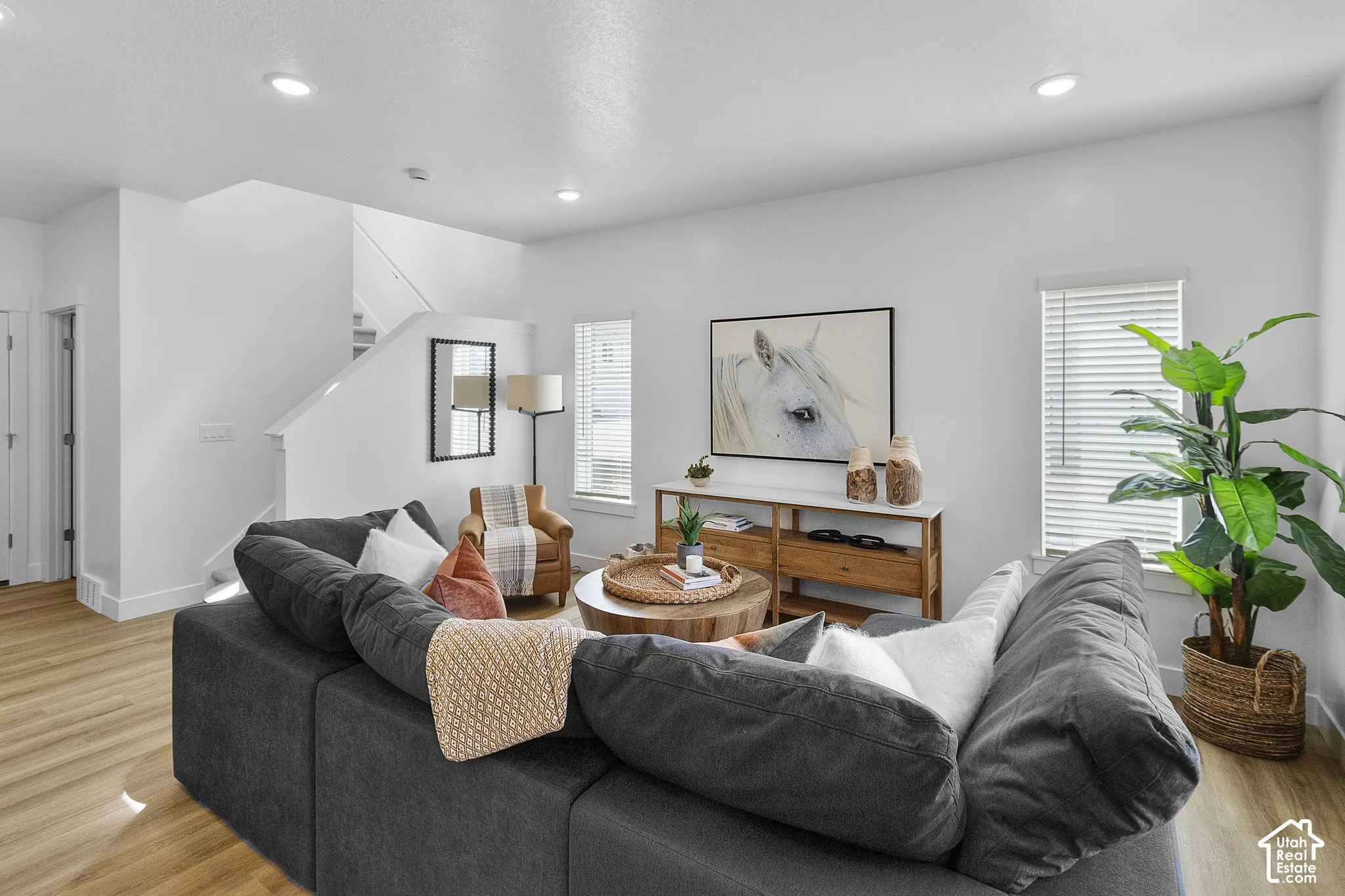 Recessed ceiling lighting, wood-finish flooring, white walls, and a staircase with white risers