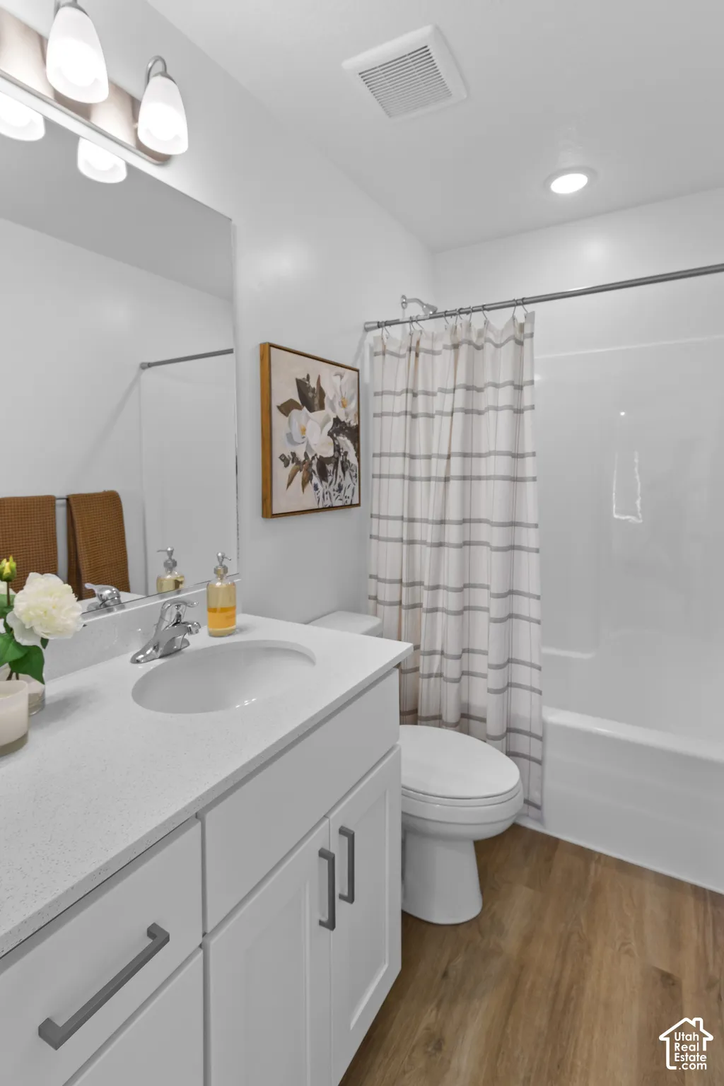 White vanity with a light-colored countertop, undermount sink, and chrome-finish faucet