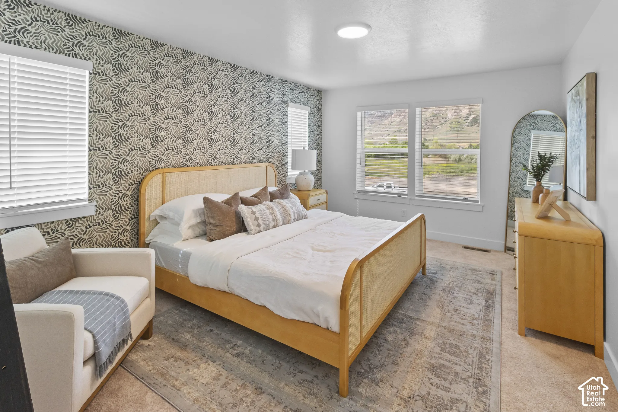 Patterned accent wall, twin windows, flush-mount ceiling light, and light-toned flooring