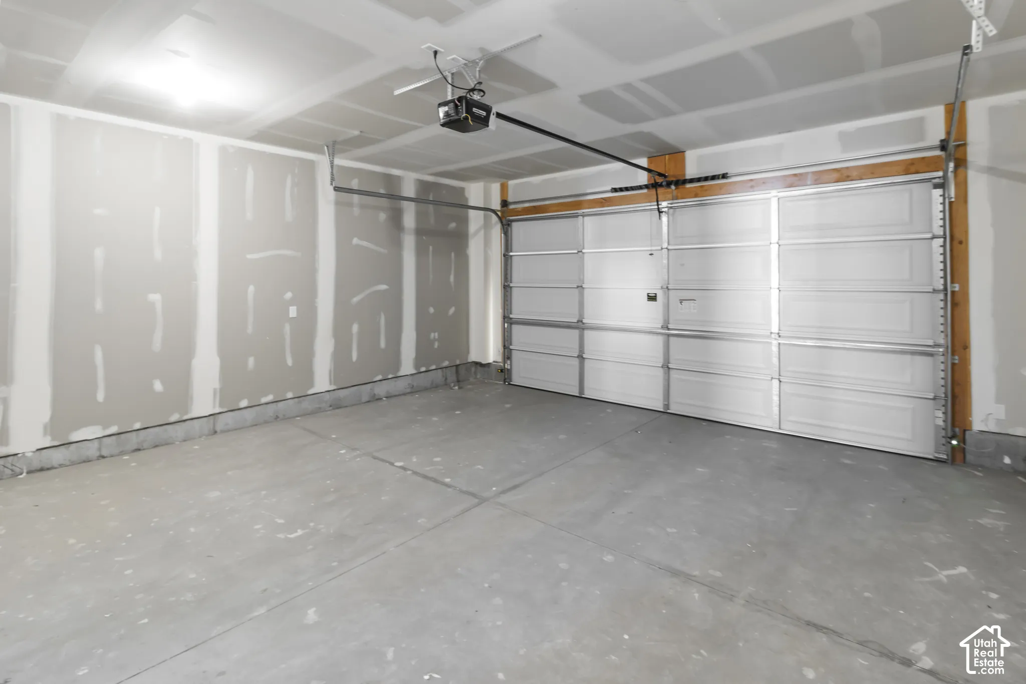 Spacious garage with an automatic overhead door, concrete flooring, and exposed framing