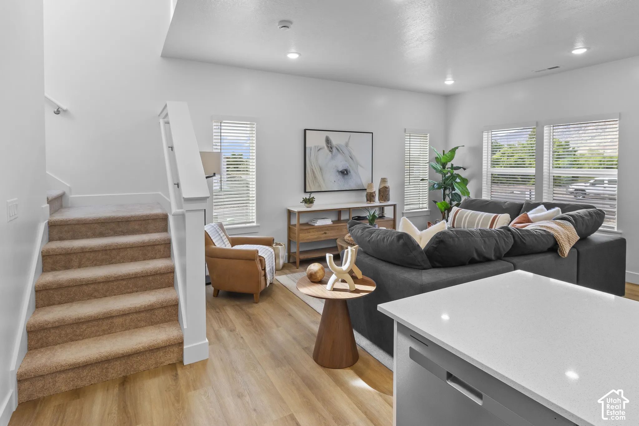 Open concept living area featuring wood-finish flooring, recessed lighting, and multiple windows with blinds