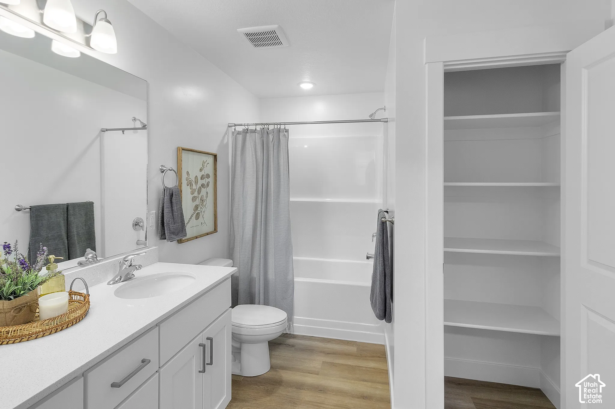 White vanity with a solid surface countertop, undermount sink, and chrome faucet