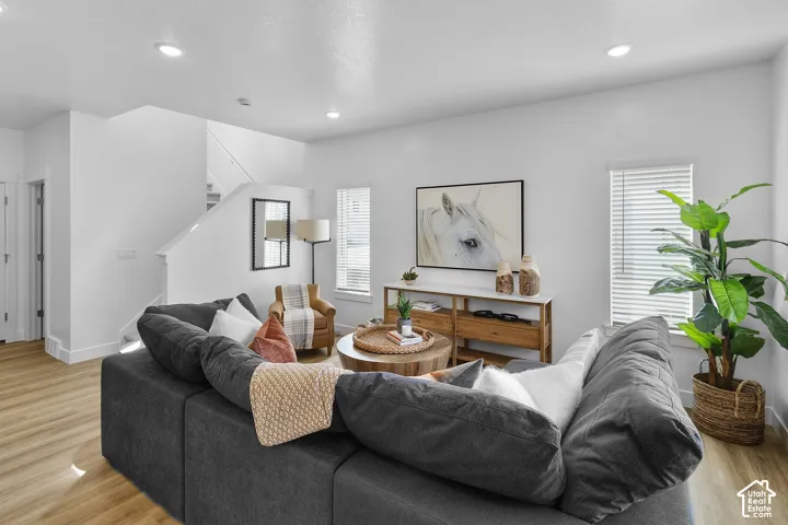 Recessed ceiling lighting, wood-finish flooring, white walls, and a staircase with white risers