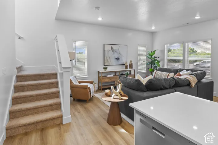 Open concept living area featuring wood-finish flooring, recessed lighting, and multiple windows with blinds