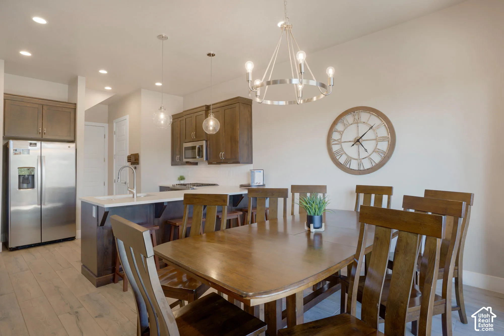Open-concept living space featuring wood-finish flooring, recessed lighting, and a stainless steel refrigerator