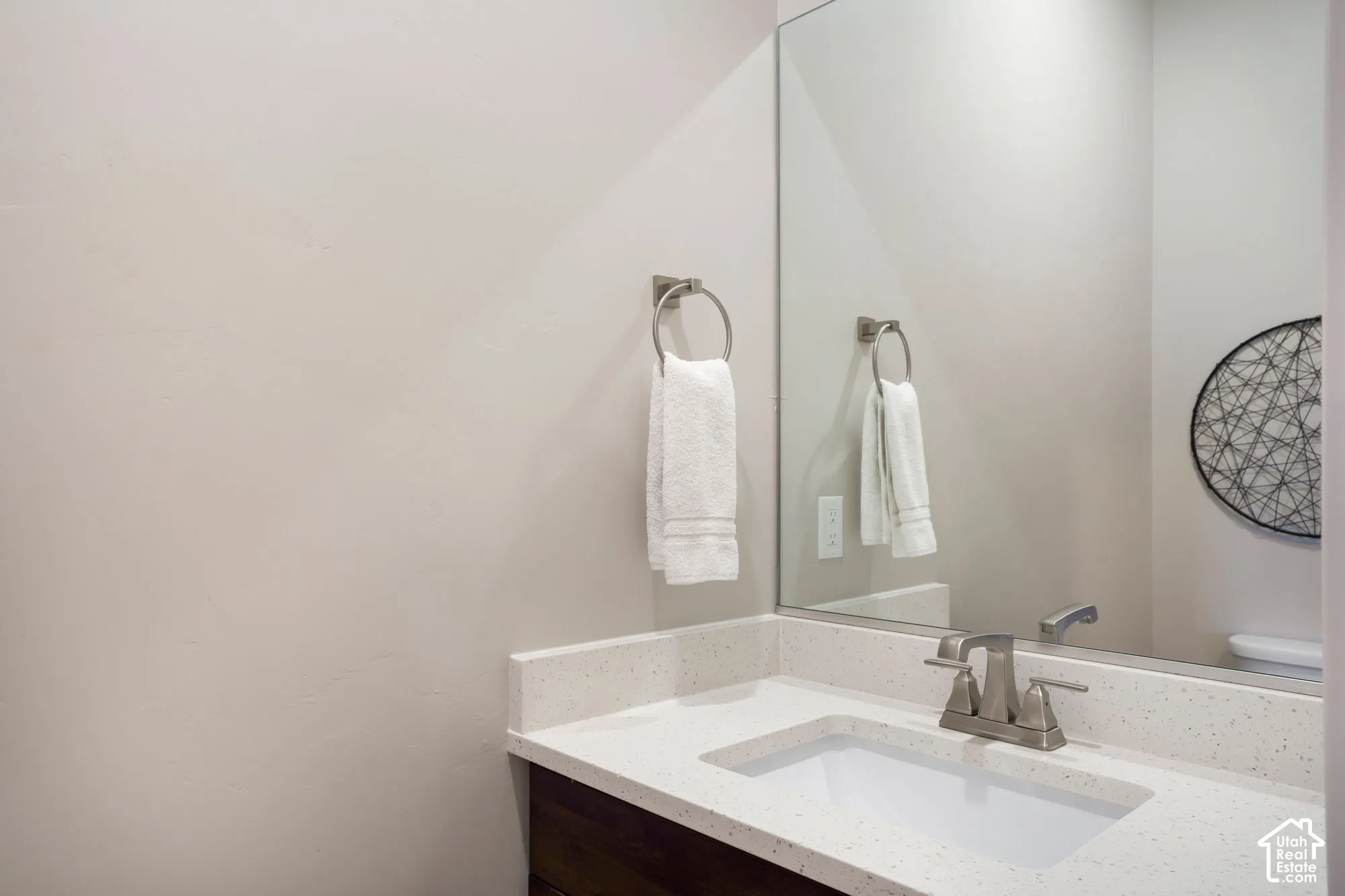Vanity featuring a white rectangular sink, light-toned countertop, and brushed nickel faucet