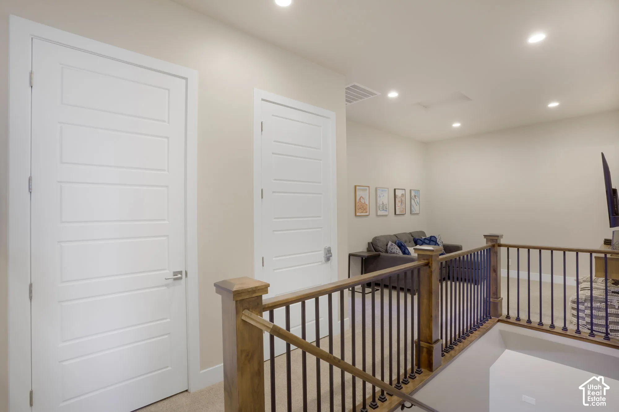 Neutral wall color, recessed lighting, wood-finish handrail, black metal balusters, and carpeted flooring