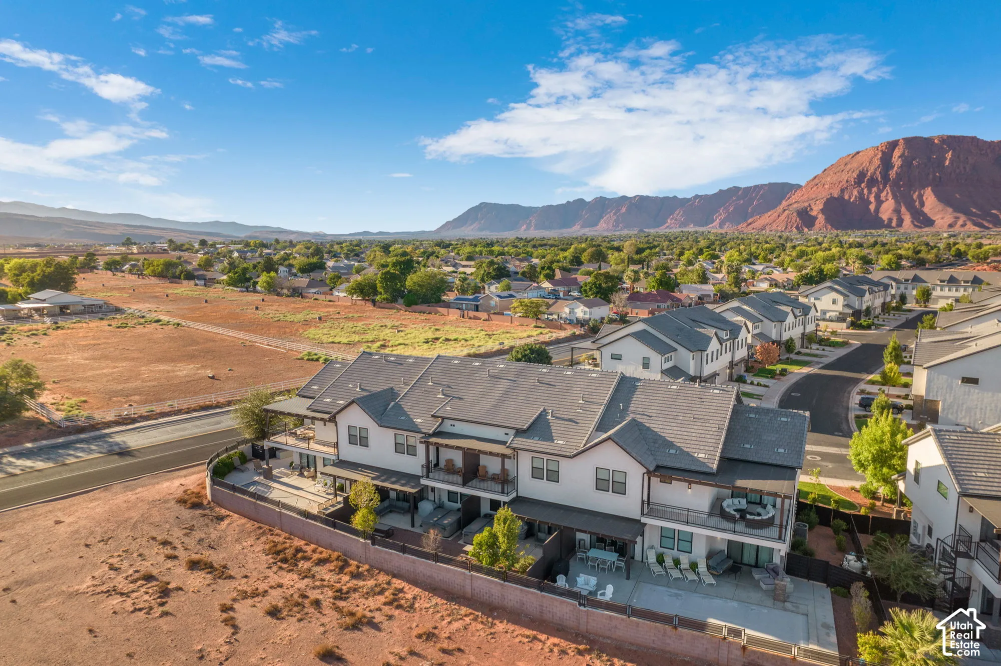 Modern townhome development with multiple balconies, a private patio, and a landscaped perimeter, set against a mountainous backdrop