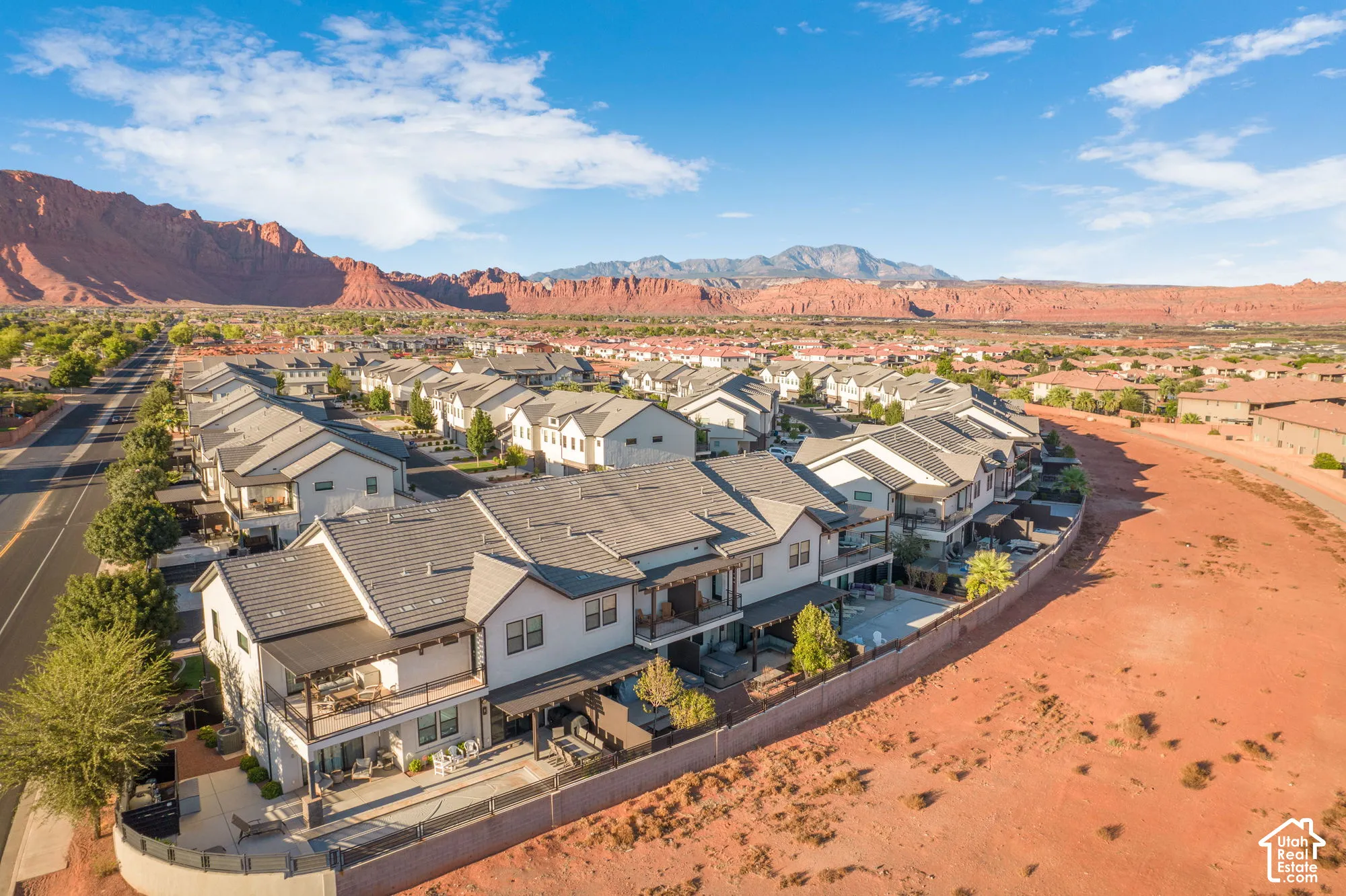 Modern desert community with a paved road, mountain backdrop, and multiple residences featuring balconies