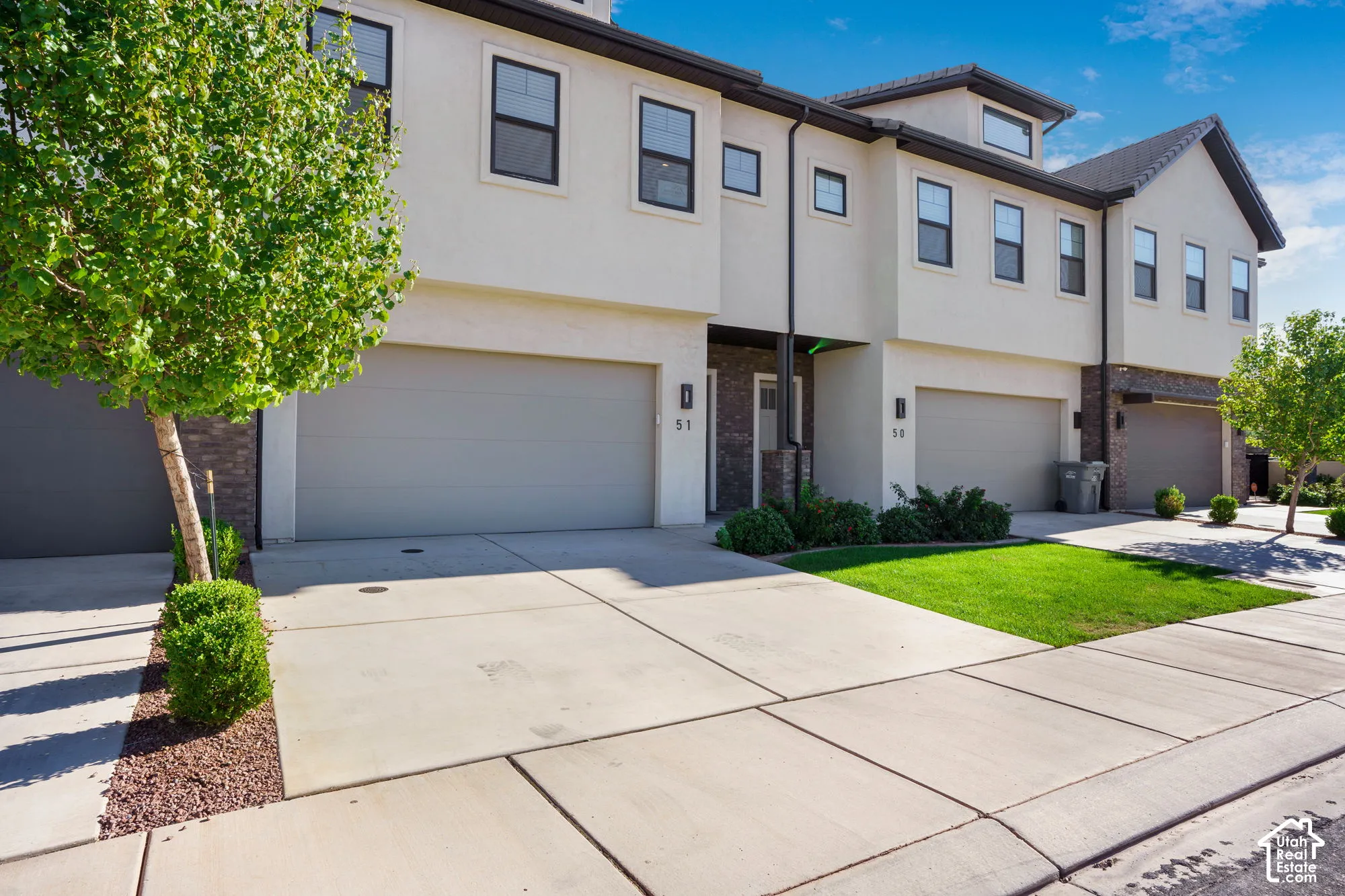Contemporary townhome-style exterior with light-colored stucco and dark trim