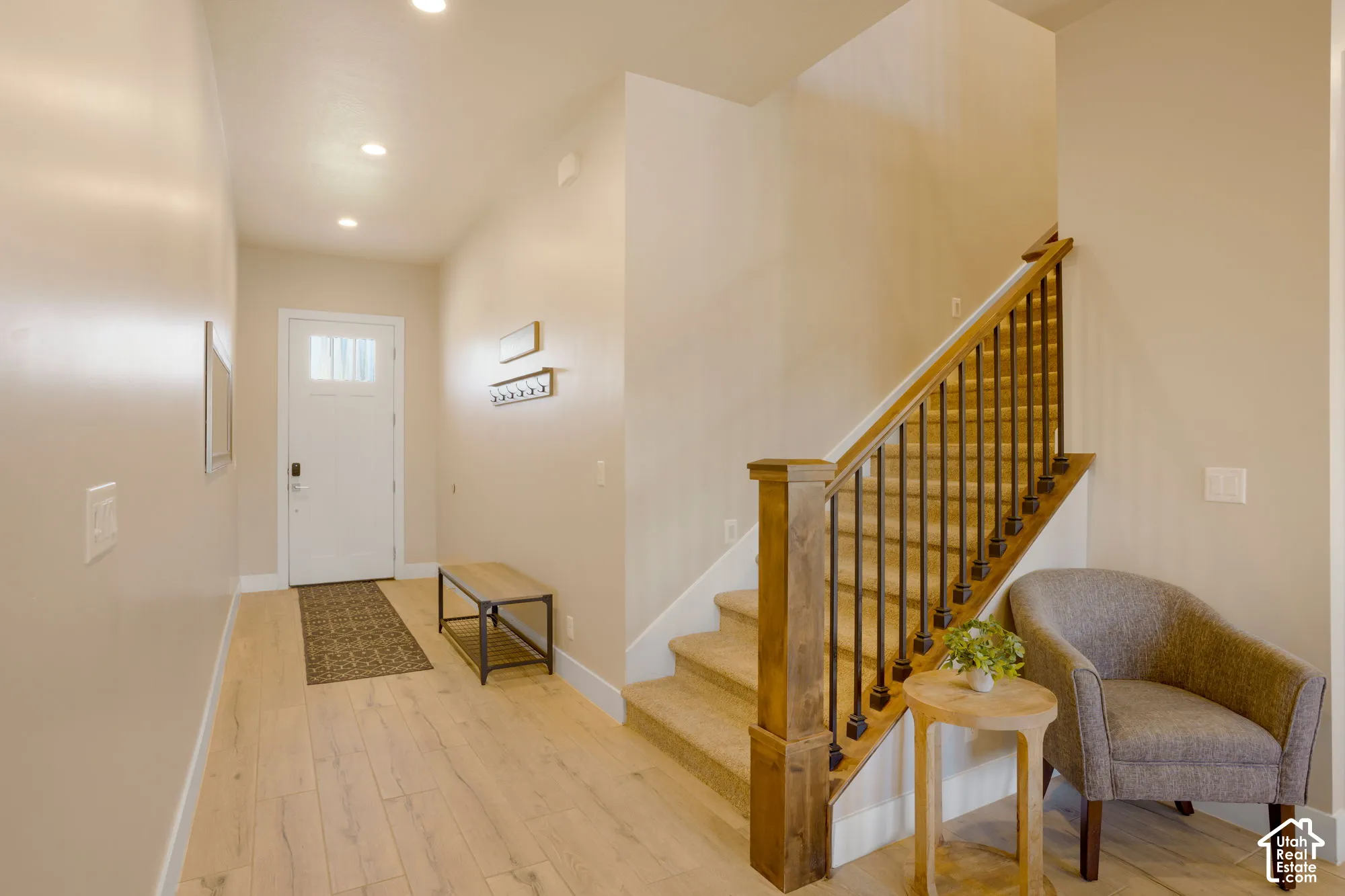 Entryway featuring wood-finish flooring, recessed lighting, a staircase with carpeted treads, and a wood newel post with metal balusters