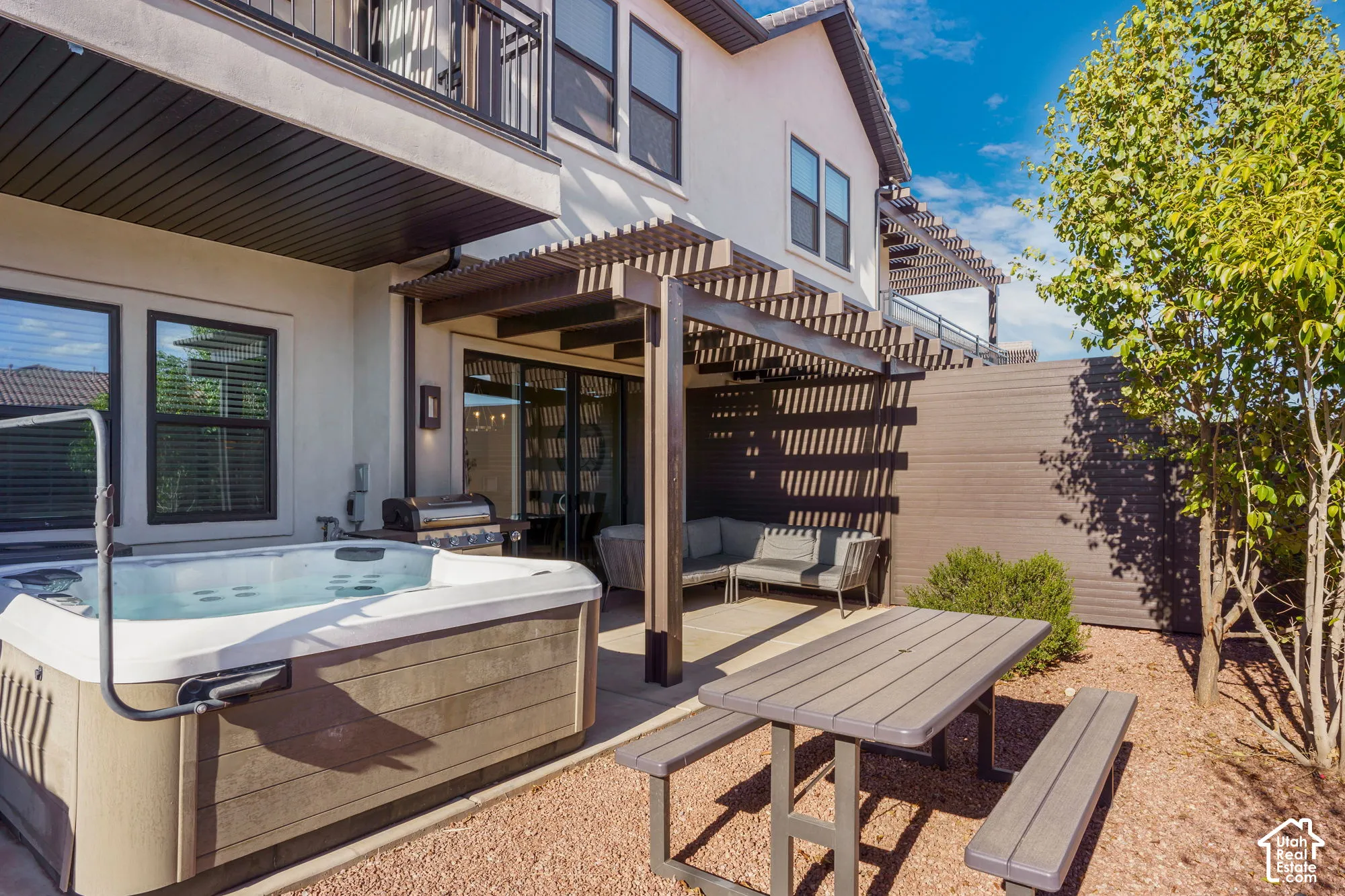 Outdoor spa and grill area with an attached pergola for shaded outdoor living