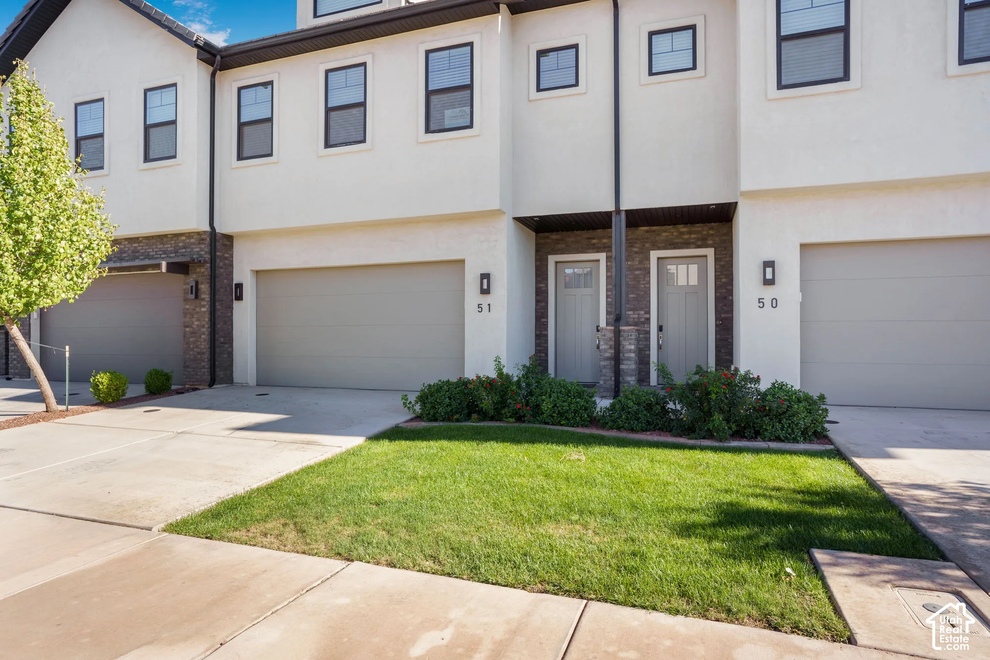 Modern stucco exterior with dark-framed windows, integrated garage, and stone accent columns