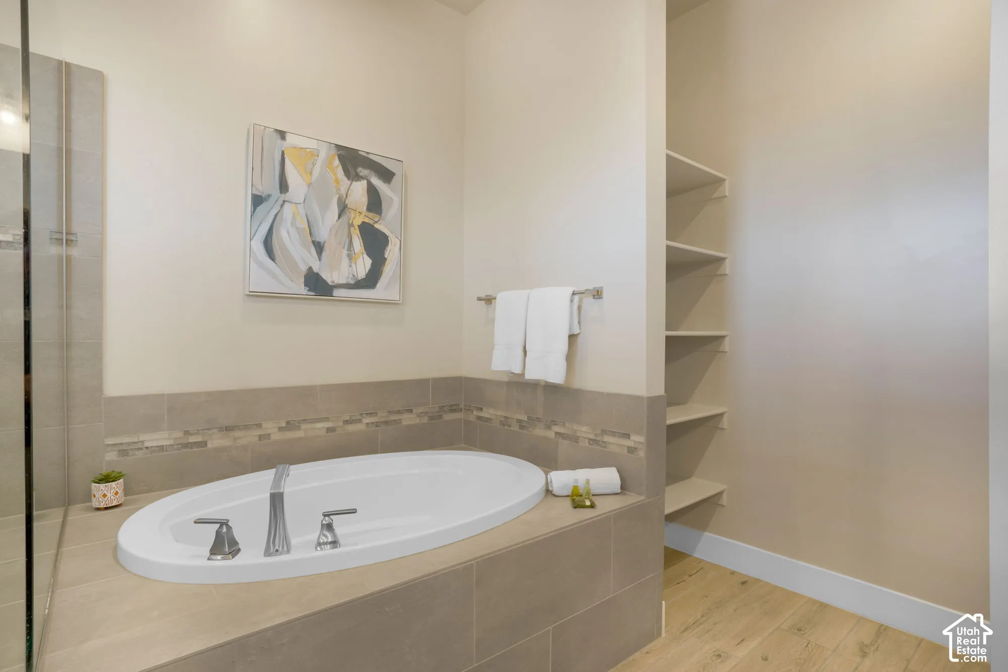 Built-in soaking tub with brushed nickel fixtures, tiled surround, glass shower enclosure, and integrated open shelving