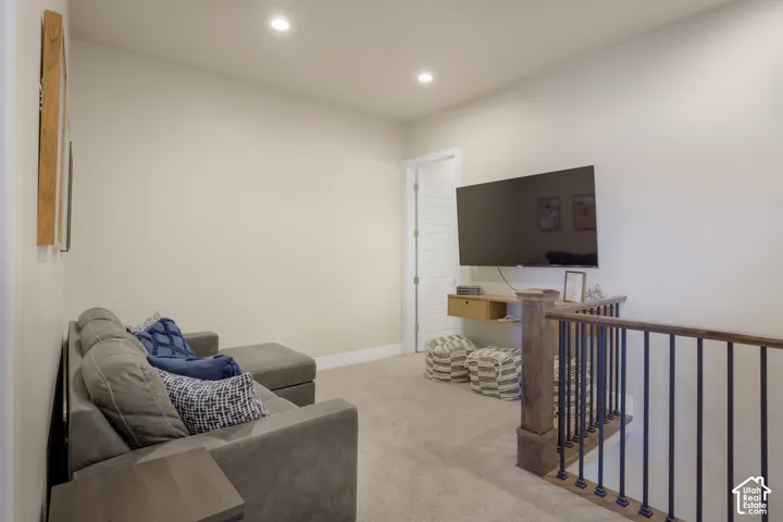 Recessed ceiling lighting, light-colored carpeting, white walls, and a wood and iron railing