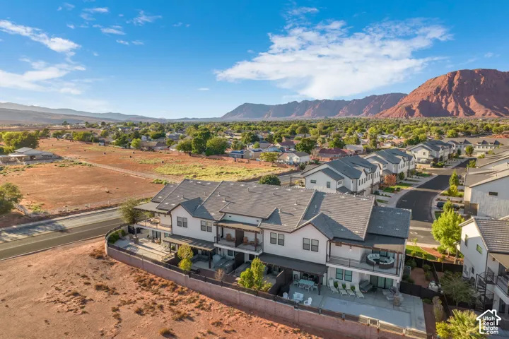 Modern townhome development with multiple balconies, a private patio, and a landscaped perimeter, set against a mountainous backdrop