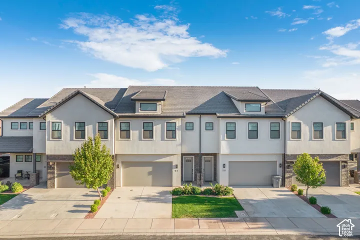 Contemporary townhome exteriors featuring light stucco, dark-framed windows, and integrated garages