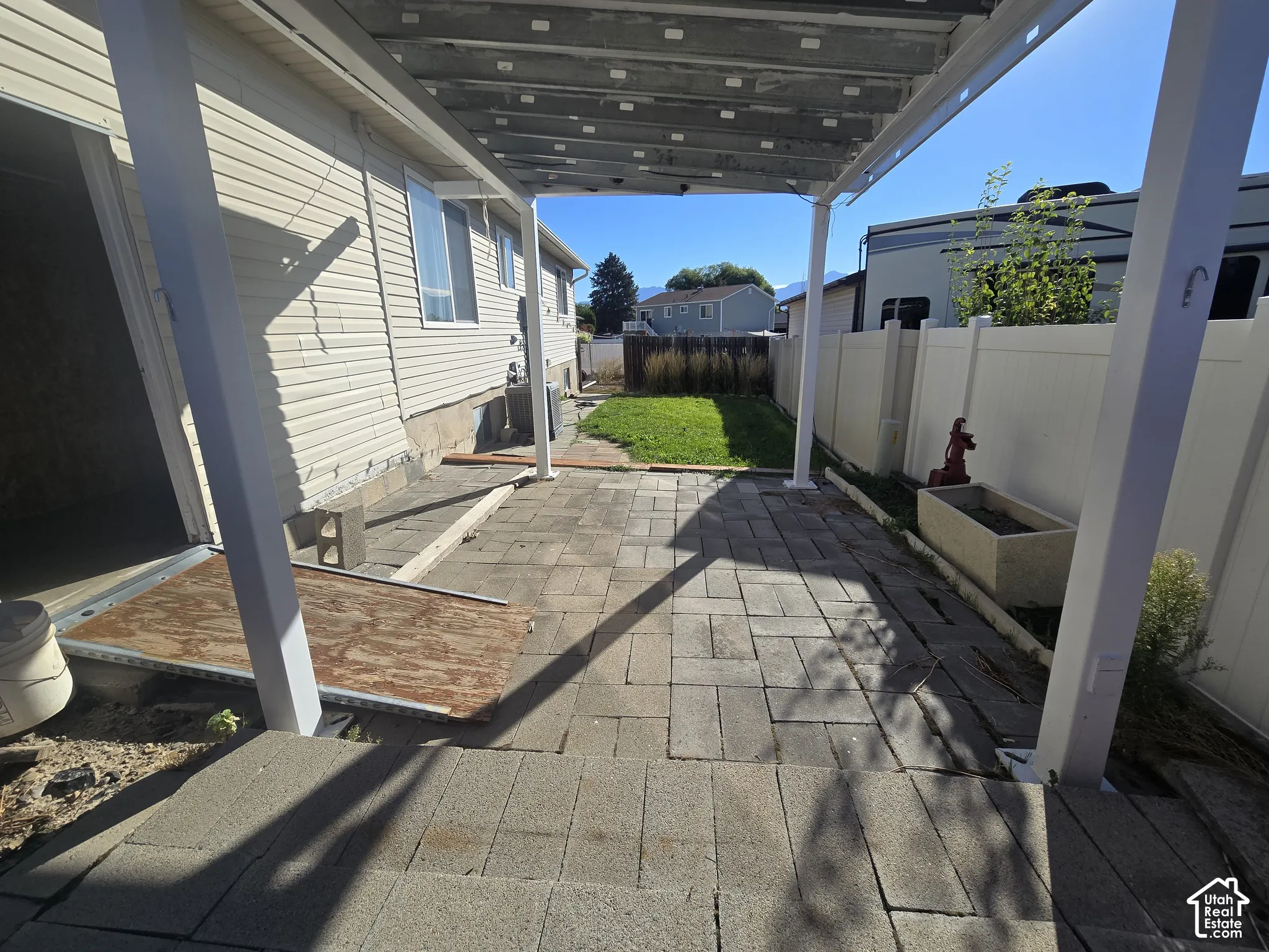 Paved patio area, white vinyl fencing, and a covered pergola structure