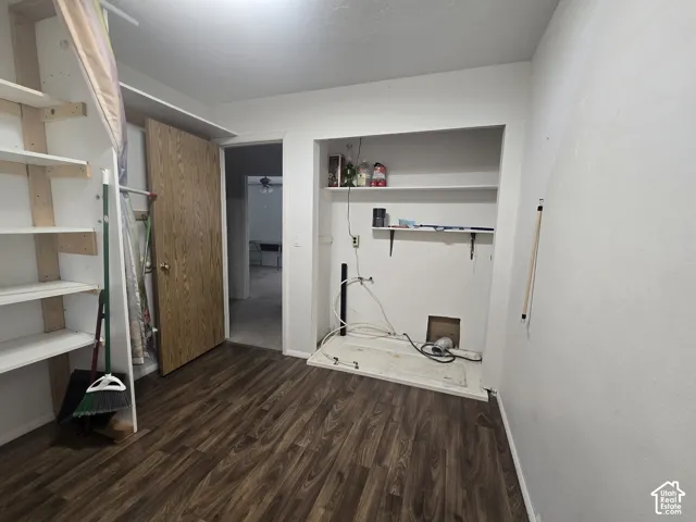 Laundry area featuring wood-finish flooring and built-in shelving in bedroom upstairs