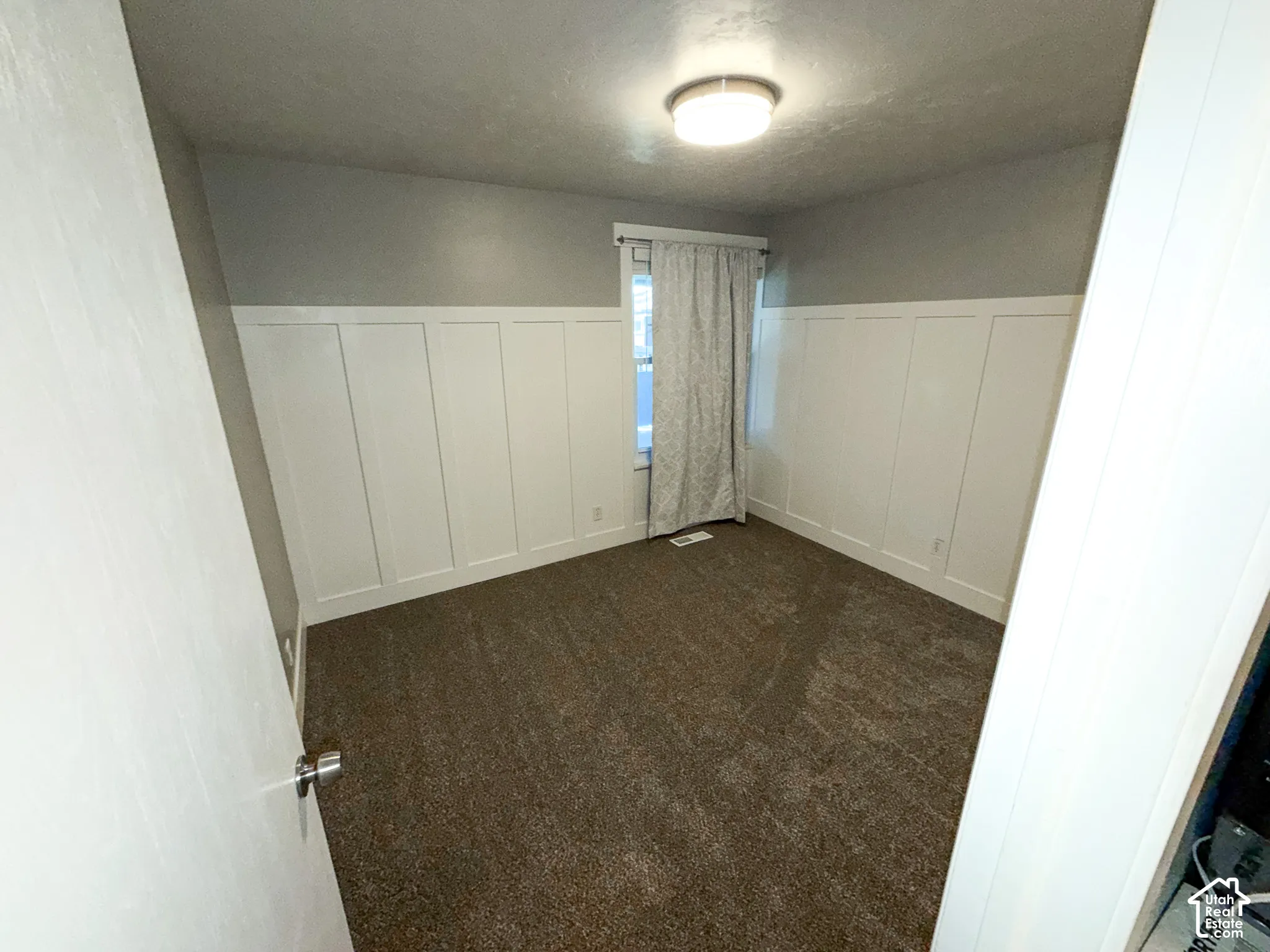 Board and batten wainscoting with a neutral wall color, plush carpet, and a flush-mount ceiling light fixture