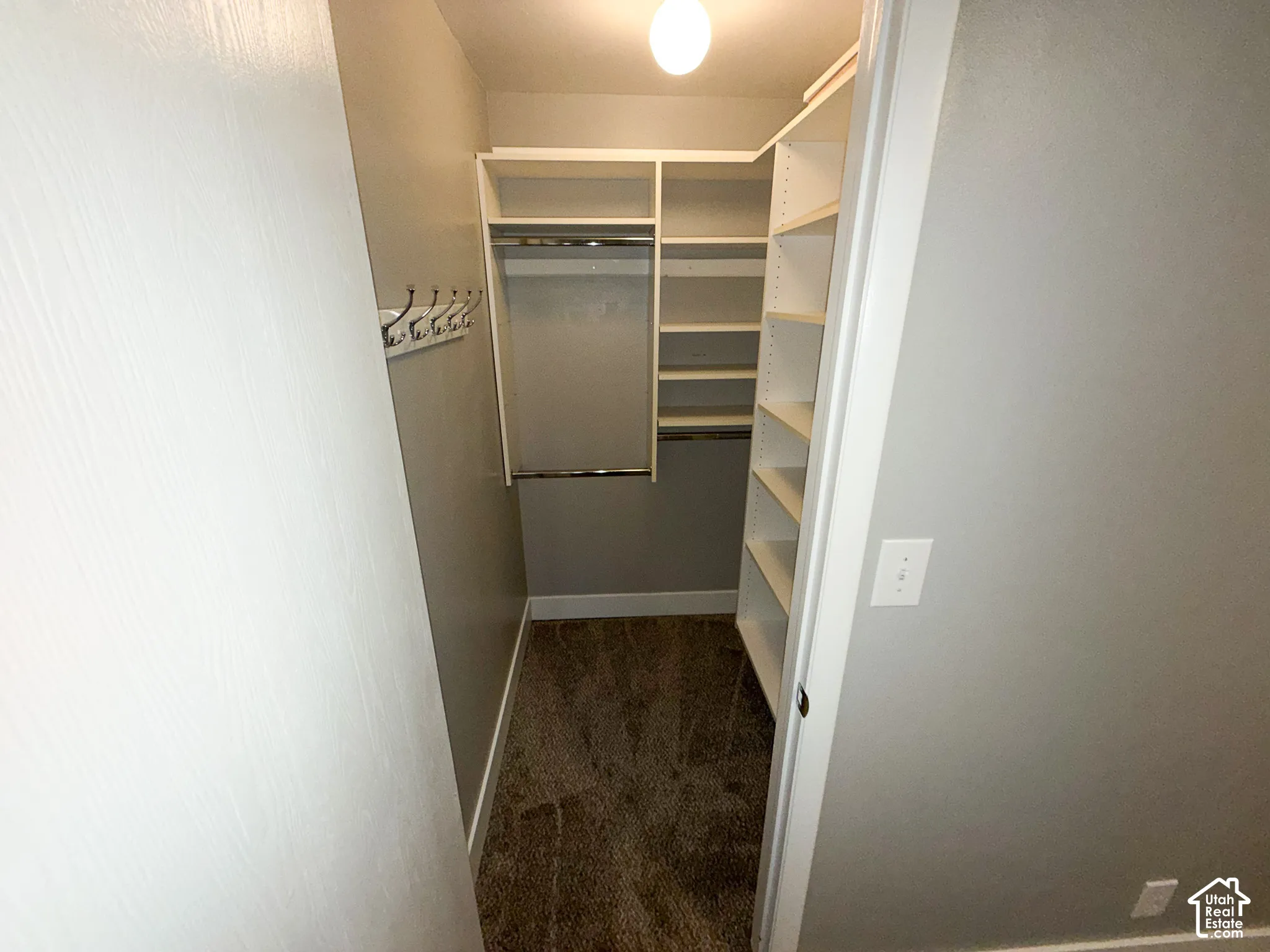 U-shaped closet system featuring white shelving, hanging rods, and a coat rack
