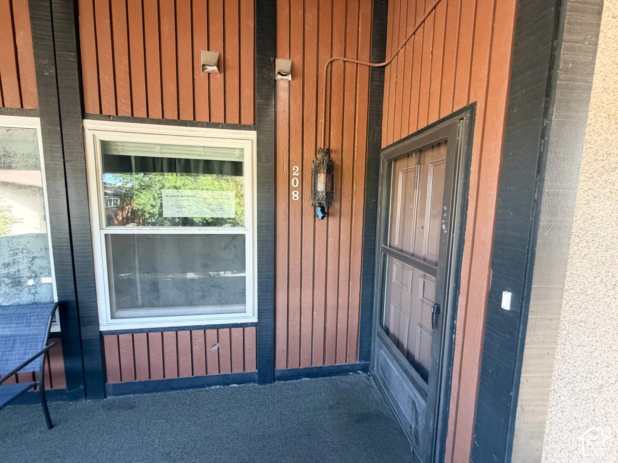 Vertical siding with contrasting trim, a white-framed window, and an exterior sconce