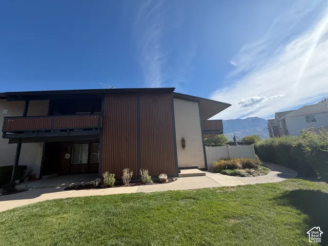 Building exterior featuring wood-paneled siding, a private balcony, and a manicured lawn