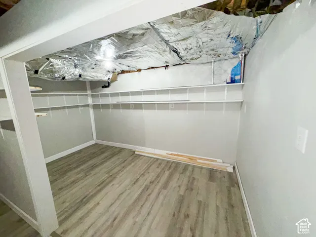 Wood-finish flooring with light gray walls, featuring white shelving units