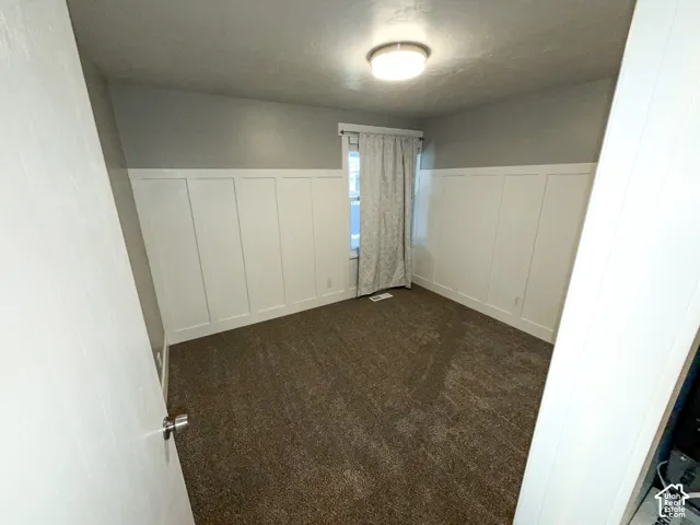 Board and batten wainscoting with a neutral wall color, plush carpet, and a flush-mount ceiling light fixture