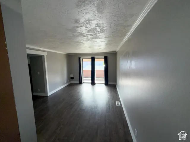 Wood-finish flooring throughout, sliding glass door with dark drapes, and white crown molding