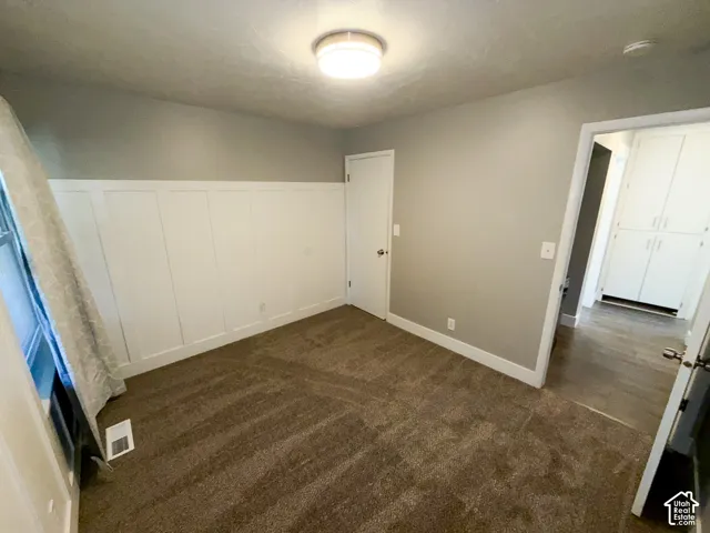 Wall paneling accent with neutral paint, overhead flush mount lighting, and plush carpeting