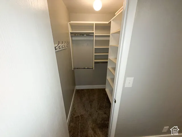 U-shaped closet system featuring white shelving, hanging rods, and a coat rack