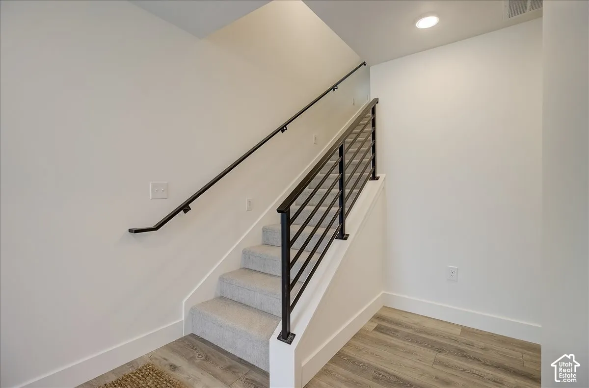 Staircase featuring carpeted treads, a modern metal railing, and a matching handrail