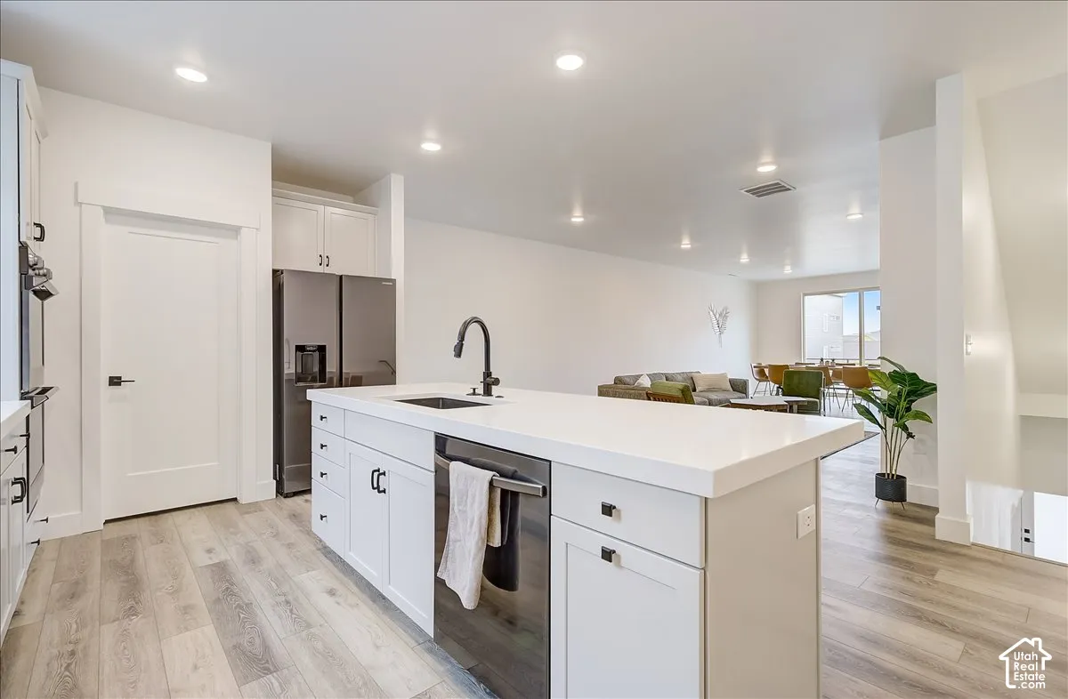 Kitchen island with white countertop, integrated sink, black faucet, and built-in dishwasher