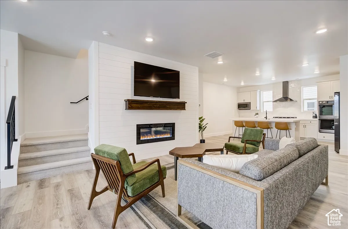 Living area featuring wood-finish flooring, a contemporary fireplace with a wood mantle, and shiplap wall detailing