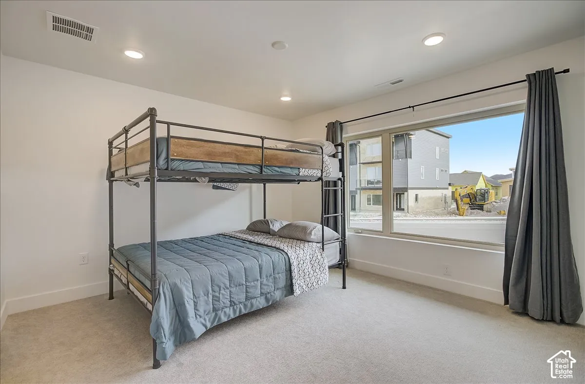 Recessed lighting, light-toned carpeting, and a large window with roller shades