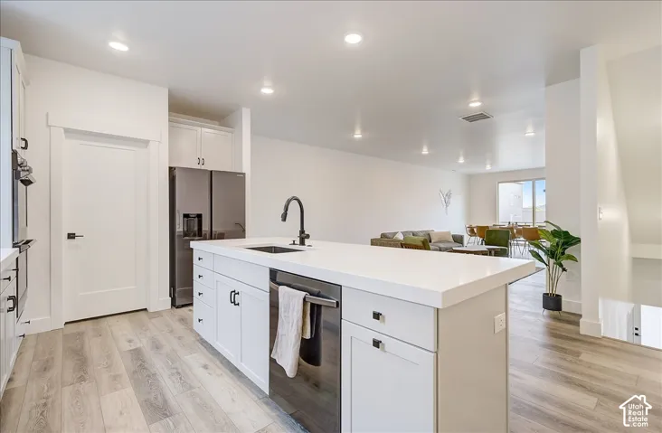 Kitchen island with white countertop, integrated sink, black faucet, and built-in dishwasher