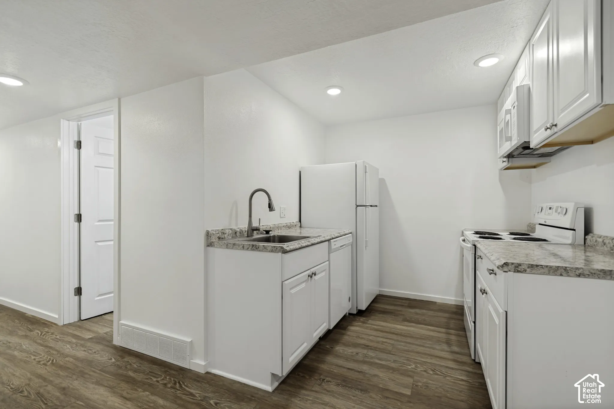Full kitchen featuring white cabinetry, integrated appliances, wood-finish flooring, and recessed lighting