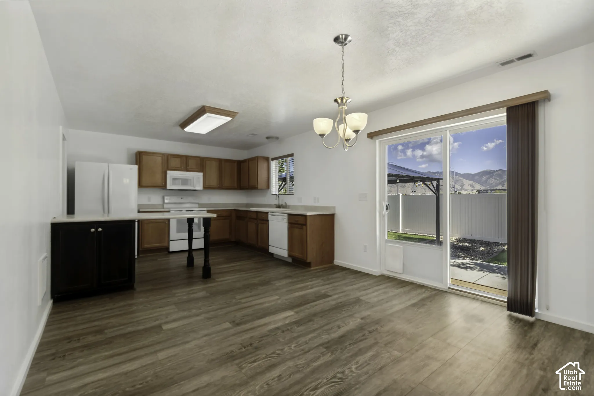Kitchen with wood-finish flooring, white appliances, and warm-toned cabinetry