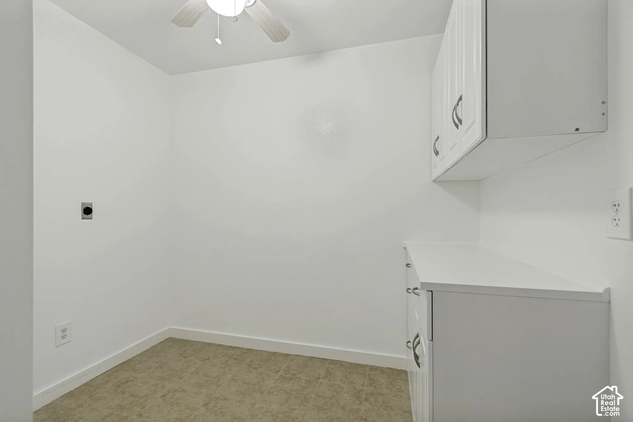 White cabinetry with curved pulls, white countertop, and ceiling fan