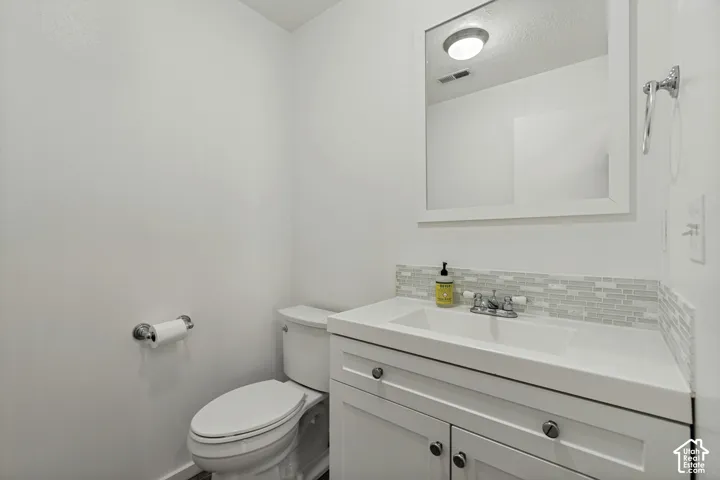 White vanity with chrome hardware, integrated sink, and mosaic tile backsplash