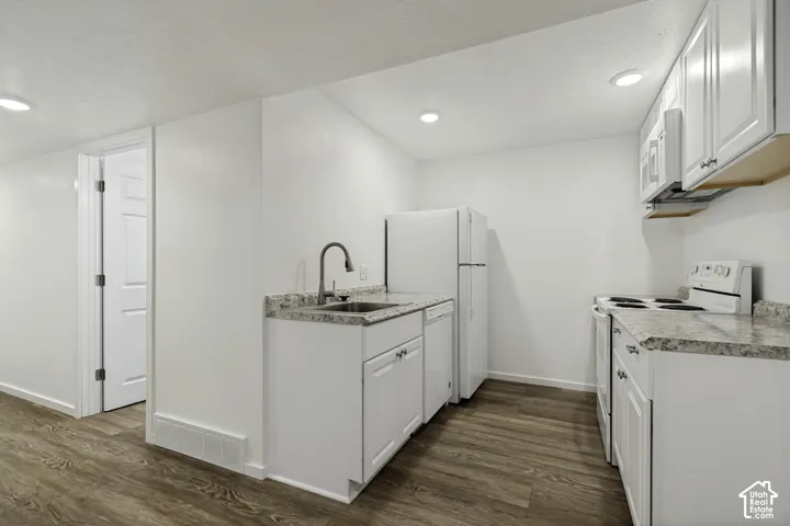 Full kitchen featuring white cabinetry, integrated appliances, wood-finish flooring, and recessed lighting