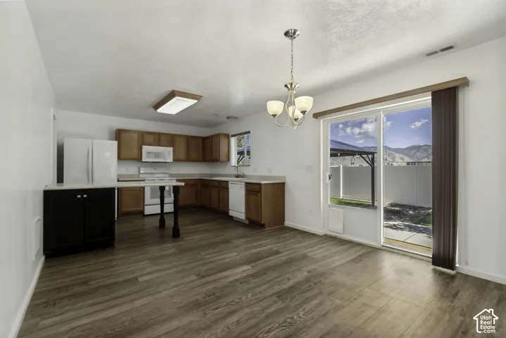Kitchen with wood-finish flooring, white appliances, and warm-toned cabinetry
