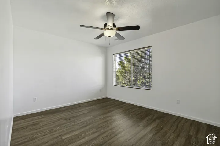 Wood-finish flooring with white walls and a ceiling fan