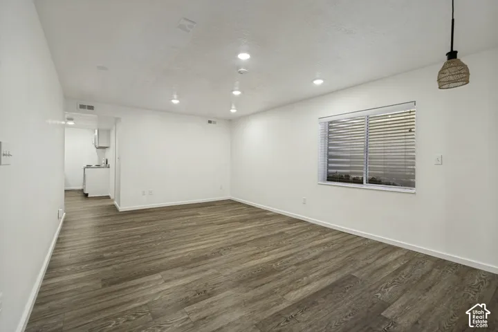 Expansive room featuring wood-finish flooring, recessed lighting, and a window with blinds
