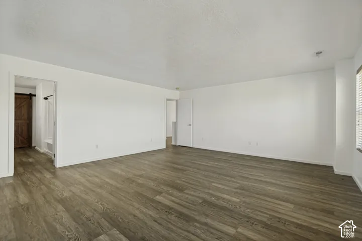 Expansive room featuring wood-finish flooring, white walls, and a window with blinds