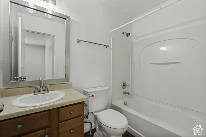 Bathroom featuring a vanity with wood-finish cabinetry, an integrated sink, and a framed mirror