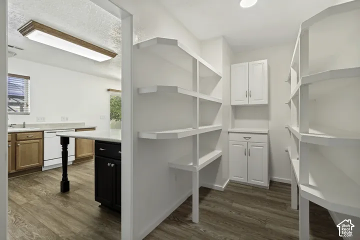 Spacious walk-in pantry with extensive built-in shelving, wood-finish flooring, recessed lighting, and white cabinetry